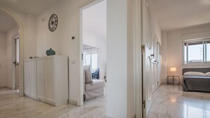 A spacious hallway with marble flooring, white cabinets, and a clock on the wall.