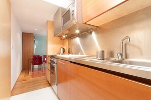 A modern kitchen with stainless steel appliances, wooden cabinetry, and a built-in oven. - Kalsa Miniloft by Wonderful Italy (Palermo)