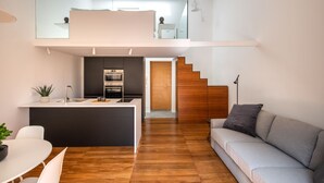 Un intérieur moderne comprenant une cuisine, un coin repas et un canapé gris.