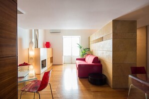 A modern living room with a wooden floor, a red sofa, a glass table, and a red chair. - Kalsa Miniloft by Wonderful Italy (Palermo)