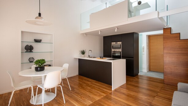 Une cuisine moderne avec un îlot central, des chaises blanches et une table à manger.