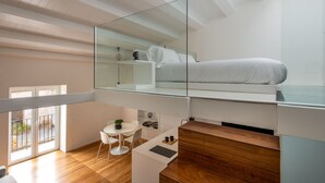 Une chambre de style loft moderne, dotée d’un plafond en verre, d’un lit, d’un bureau et d’un petit coin salon.