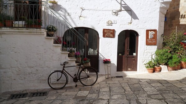 Un bâtiment blanc avec un vélo garé devant, un escalier et des plantes en pot.