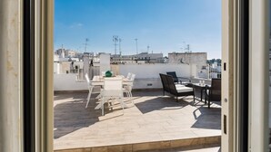 A rooftop terrace with a table and chairs, a view of the cityscape, and a clear sky. - Terrazza Isabella by Wonderful Italy (Ostuni)