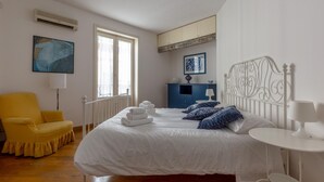 A bedroom with a large bed, a chair, a desk, and a dresser.