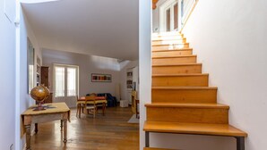 A staircase leading to a second floor, wooden flooring, a globe on a table, and a dining area with chairs and a table.