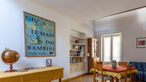 A room with a dining table, chairs, a globe, a bookshelf, a sofa, and a window.