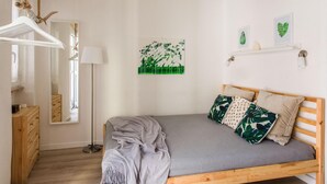 Un dormitorio con una cama de madera, una manta gris y un espejo.