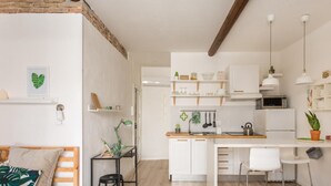 Una cocina moderna con armarios blancos, encimera de madera y un comedor con una silla blanca.