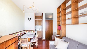 Un espacio habitable compacto con kitchenette, comedor y sofá.