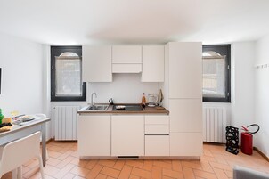 Una cocina compacta con gabinetes blancos, un lavamanos y una ventana.