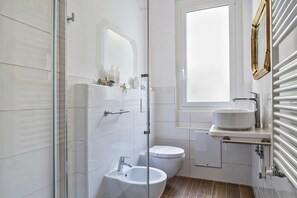 A modern bathroom with a glass shower enclosure, a white sink, and a toilet.