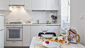 A modern kitchen with white cabinets, a gas stove, and a dining area set with a table, chairs, and a decorative vase.