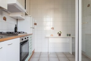 A compact kitchen with white cabinets, a gas stove, a built-in oven, and a small countertop. - White Sea by Wonderful Italy - Villetta Merida (Carovigno)