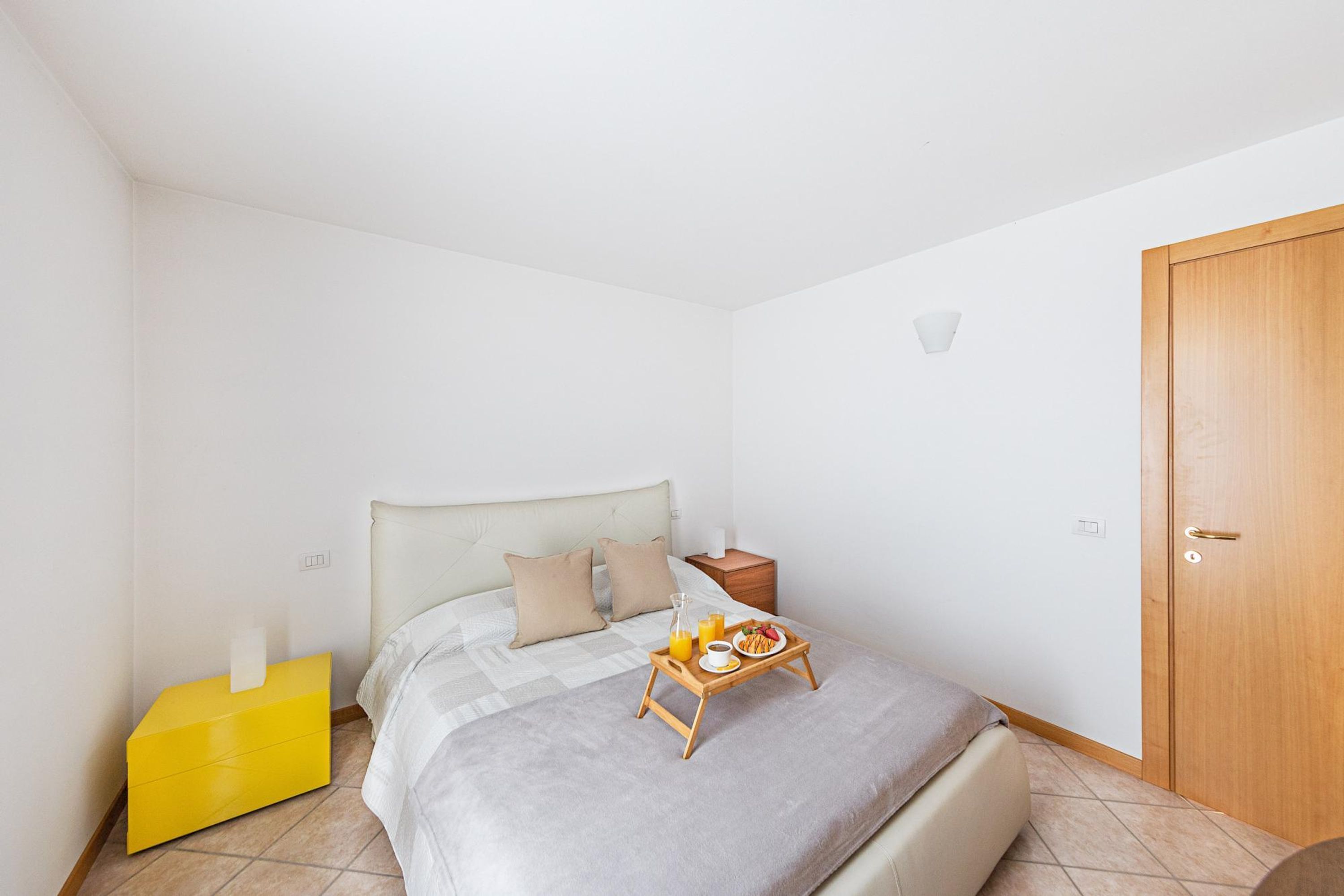 A bedroom with a bed, bedside table, and a tray with breakfast items.