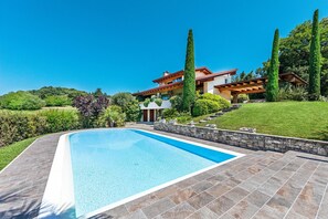 A modern house with a swimming pool, stone pathway, and lush greenery. - Villa Vittoria con Piscina e Vista Lago by Wonderful Italy (Manerba del Garda)
