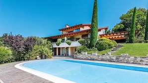 Ett modernt hus med en swimmingpool, stenmurar och en välskött trädgård.