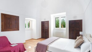 A bedroom with a bed, a chair, wooden wardrobes, and a window. - Villa Marangi con Piscina (Taurisano)
