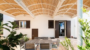A covered patio with a table and chairs, a door, and windows with shutters. - Villa Marangi con Piscina (Taurisano)