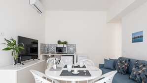 Et moderne, minimalistisk opholdsrum med spiseplads, køkken og siddeområde.