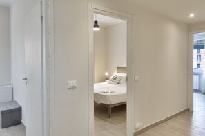 A bedroom with a bed, bedside lamp, and a view of the outside.