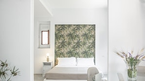 A bedroom with a bed, a nightstand, a lamp, a wall-mounted picture, and a vase with flowers. - Euphorbia Apartment by Wonderful Italy (Catania)