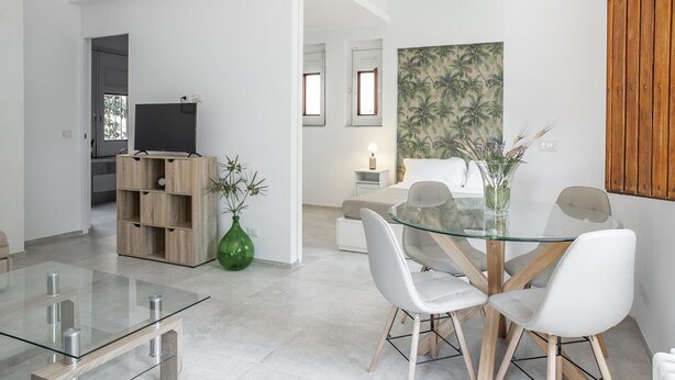 A modern living room with a glass dining table, white chairs, a wooden cabinet, and a green vase. - Euphorbia Apartment by Wonderful Italy (Catania)
