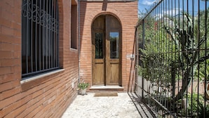A brick building with a wooden door and a metal gate. - Euphorbia Apartment by Wonderful Italy (Catania)