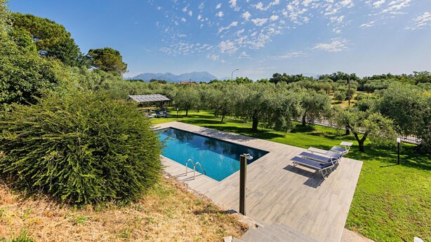 A rectangular swimming pool with a clear blue water surface, surrounded by a wooden deck. There are lounge chairs and a small gazebo in the background. - Castelletto 1 - Piscina Jacuzzi by Wonderful Italy (Polpenazze del Garda)