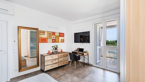 A modern bedroom with a large mirror, a wooden dresser, a desk with a laptop, and a TV. - Castelletto 1 - Piscina Jacuzzi by Wonderful Italy (Polpenazze del Garda)