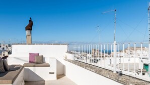 Una terraza en la azotea con un muro blanco, una chimenea y vistas de la ciudad.