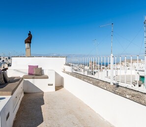 A rooftop terrace with a white wall, a chimney, and a view of the cityscape. - Casa Graziella con Terrazza by Wonderful Italy (Ostuni)