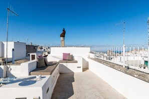A rooftop terrace with a seating area, a statue, and a view of the sea. - Casa Graziella con Terrazza by Wonderful Italy (Ostuni)