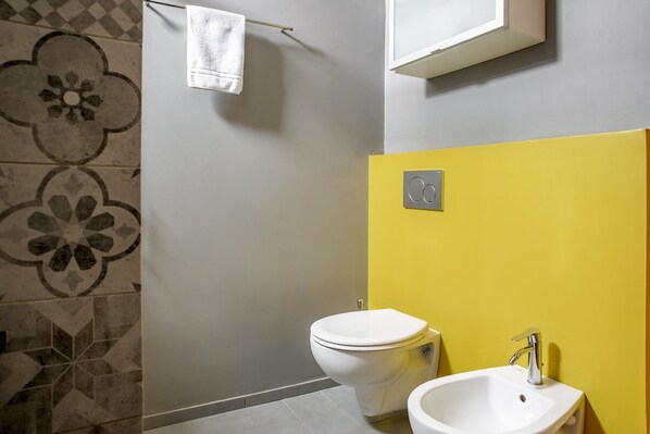 Une salle de bain équipée de toilettes, d’un lavabo et d’un porte-serviettes.