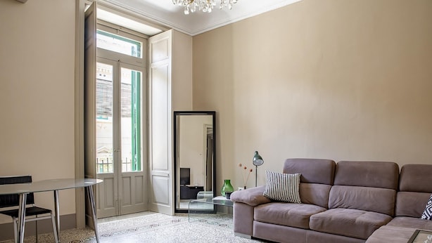 A living room with a sofa, a glass table, a chair, a mirror, and a lamp. - Cavour Apartment Near the Cathedral by Wonderful Italy (Noto)