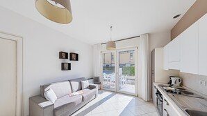 A modern kitchen with a dining area, a sofa, and a view of the outside.