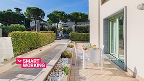 A modern outdoor patio area with a table and chairs, a pathway lined with plants, and a clear view of the surrounding neighborhood.