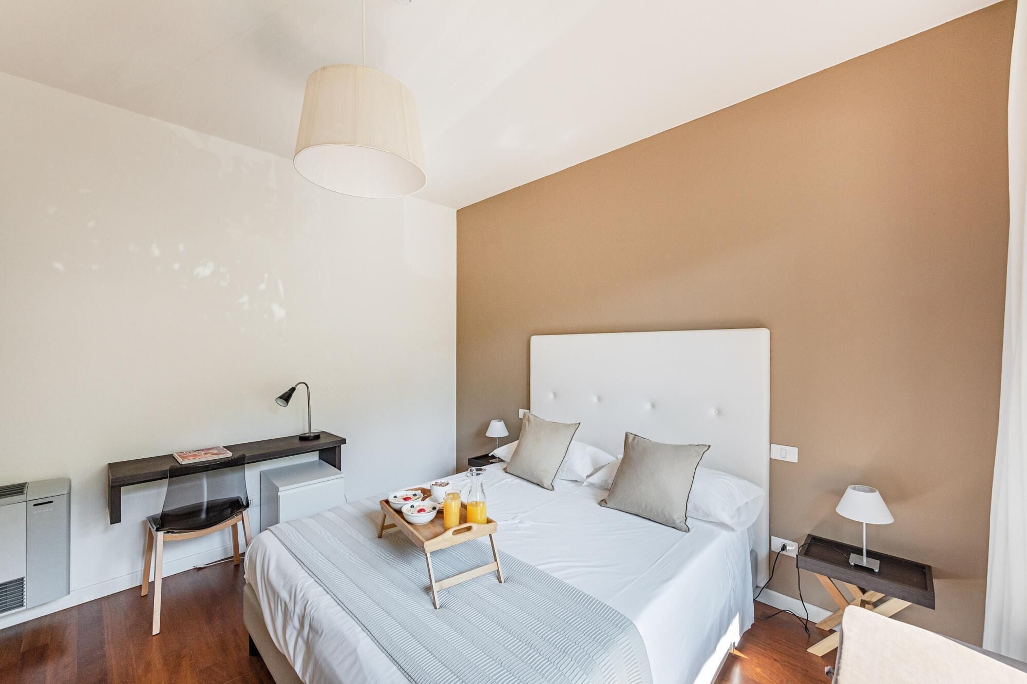 Une chambre à coucher moderne avec un lit, des tables de chevet, un bureau et une chaise.