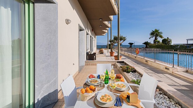 A terrace with outdoor dining, a pool, and a view of the sea.