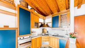 A kitchen with wooden cabinets, a stove, a microwave, and a sink. - Poggio sul Clisi 30 Apartment by Wonderful Italy (Villanuova sul Clisi)
