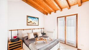 A bedroom with a bed, bedside tables, a painting, and a sliding glass door. - Poggio sul Clisi 30 Apartment by Wonderful Italy (Villanuova sul Clisi)