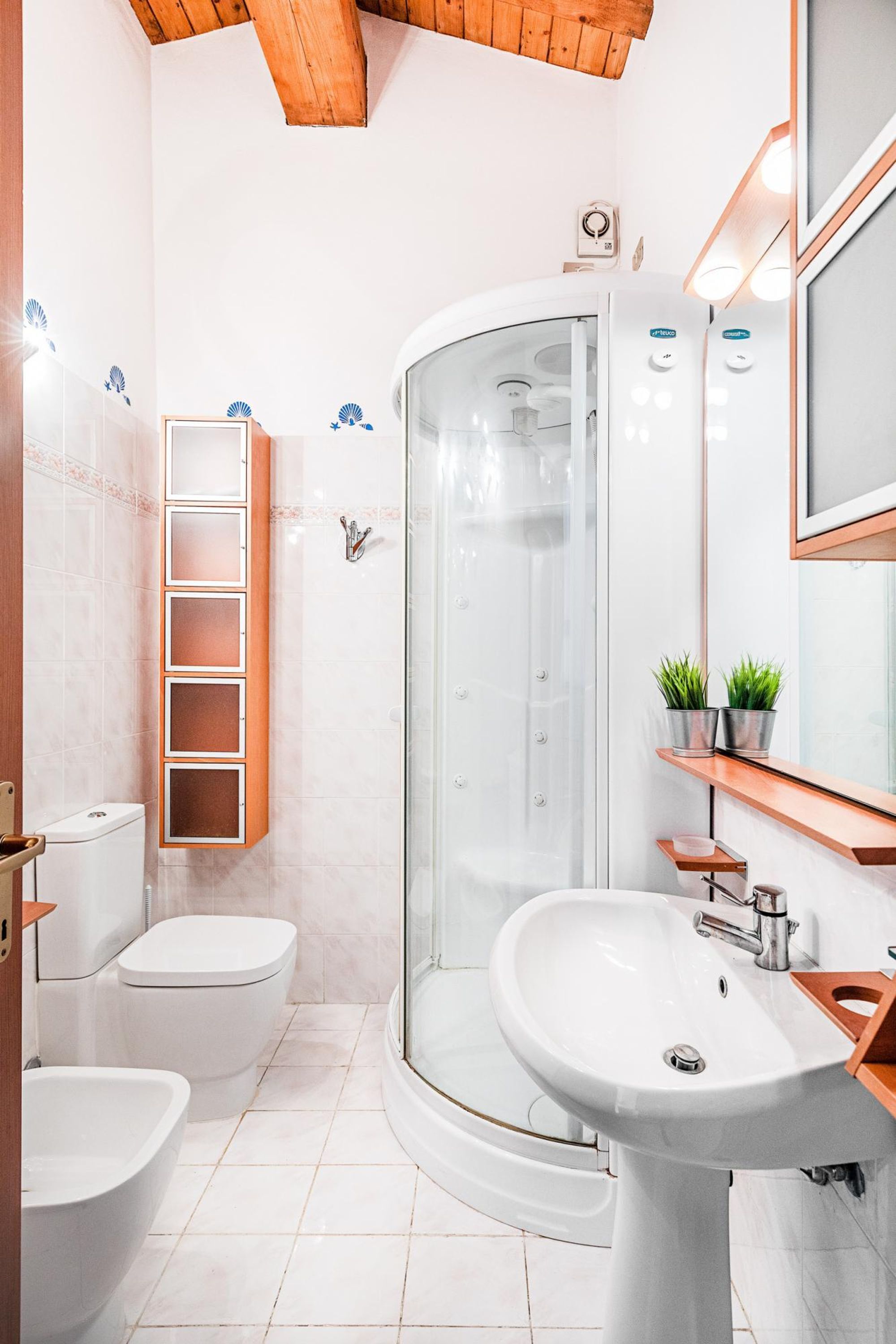 A modern bathroom with a glass-enclosed shower, a white sink, and a toilet.