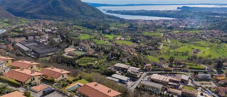 An aerial view of a town with residential buildings, green fields, and a mountain in the background.