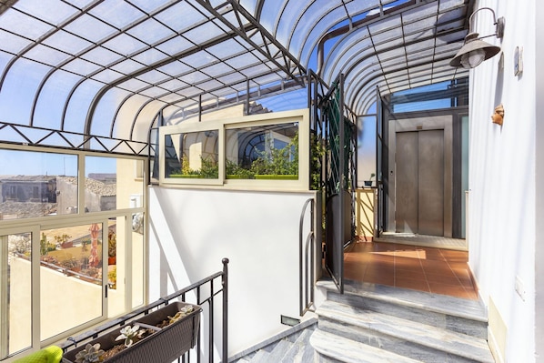 Une véranda dotée d’un toit en verre, d’un escalier et offrant une vue sur l’extérieur.