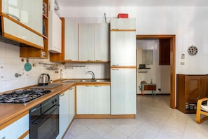 Cozinha compacta com armários brancos, fogão a gás e geladeira.