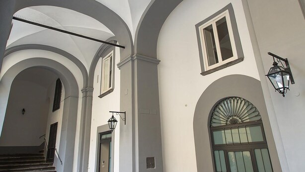 A building with arched ceilings, stone steps, and a large door with glass panels. - Il Loggiato - Stella Apartment by Wonderful Italy (Naples)