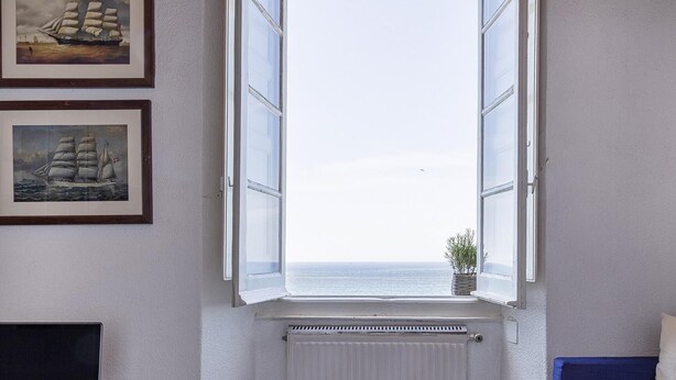 A room with a large window, a radiator below, and two framed pictures on the wall. - Il Mare di Camogli da un Obl by Wonderful Italy (Camogli)