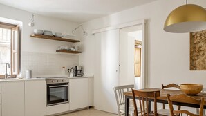 Eine moderne Küche mit weißen Schränken, einem Holzesstisch und einer hängenden Pendelleuchte.