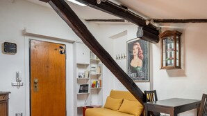 A room with a wooden staircase, a dining table with chairs, a sofa, a bookshelf, and a poster on the wall. - La Mansarda di Via Zamboni by Wonderful Italy (Bologna)