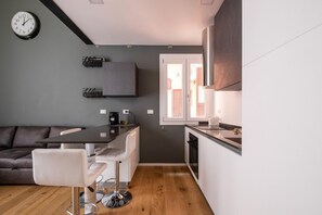 A modern kitchen with a dining area, a grey wall, and a clock. - Mazzini Elegant Apartment by Wonderful Italy (Bologna)